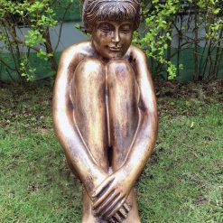 Statue of a young lady sitting in thought with a bronze finish.