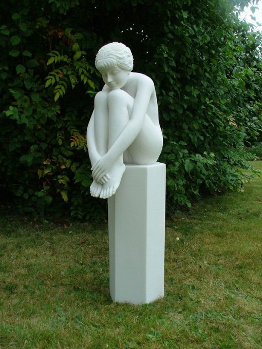 Statue of a young lady sitting on a stone plinth.