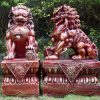 Two red dragon dogs on top of decorated stone plinths.