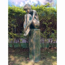 Garden ornament of a woman sitting on a stone plinth.